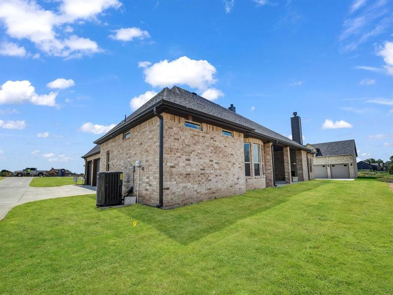 View of property exterior featuring a yard, a garage, and cooling unit