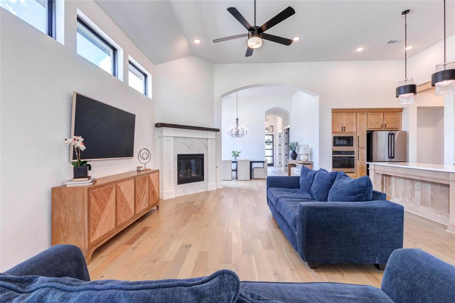 This spacious open-concept living area features a modern kitchen with a large island and pendant lighting, a cozy living room with a fireplace, and high ceilings with recessed lighting. The light wood flooring adds warmth, and the layout is perfect for entertaining. This spacious open-concept living area features a modern kitchen with a large island and pendant lighting, a cozy living room with a fireplace, and high ceilings with recessed lighting. The light wood flooring adds warmth, and the layout is perfect for entertaining.