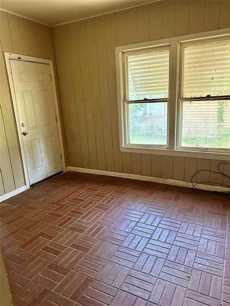 Unfurnished room featuring brick flooring and wood walls Unfurnished room featuring brick flooring and wood walls