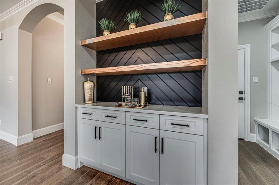 Bar featuring dark wood-type flooring and ornamental molding