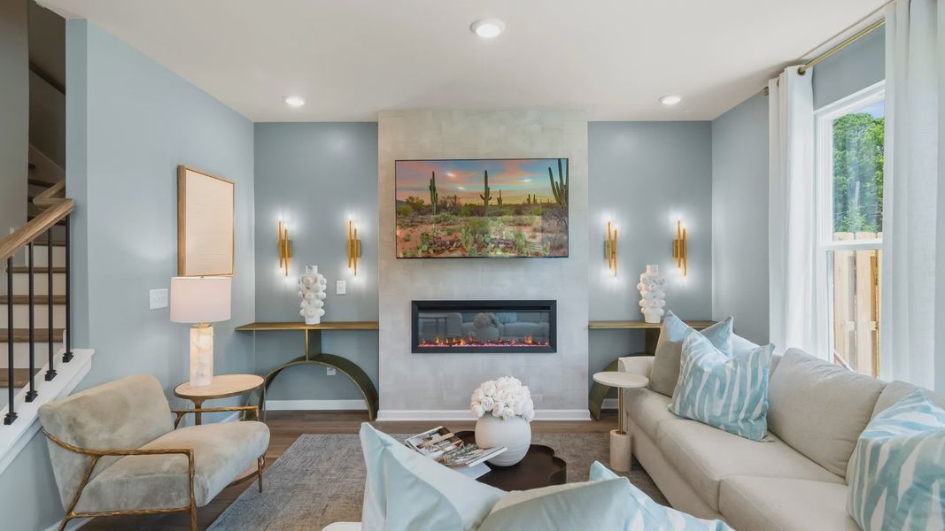 Spacious family room with electric fireplace, large windows, and open layout in new construction townhome.