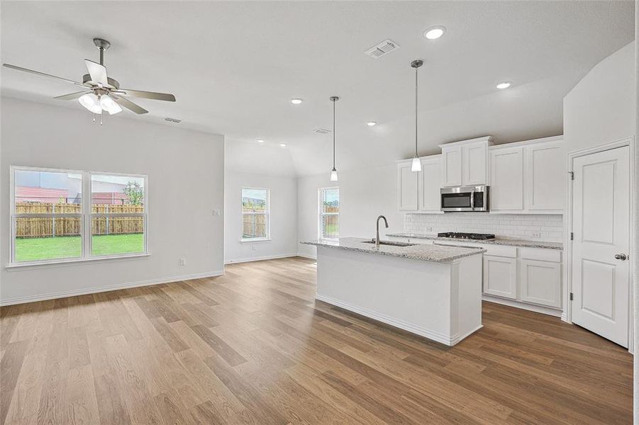 Kitchen featuring light hardwood / wood-style flooring, backsplash, stainless steel appliances, sink, and white cabinets