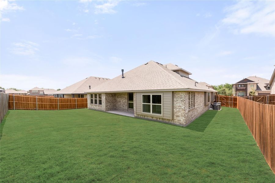 Rear view of brick home with large fenced backyard and green lawn Rear view of brick home with large fenced backyard and green lawn