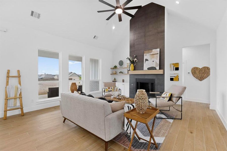 Living area featuring a large fireplace, light wood-style floors, high vaulted ceiling, ceiling fan, and recessed lighting