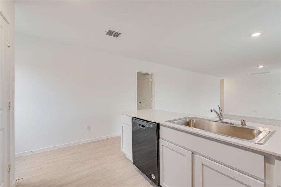 Kitchen with white cabinets, dishwasher, light hardwood / wood-style floors, and sink