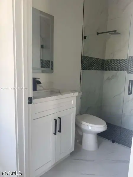 White cabinetry with black hardware, stone-finish countertop, rectangular sink, walk-in shower with glass enclosure, and patterned tile accents White cabinetry with black hardware, stone-finish countertop, rectangular sink, walk-in shower with glass enclosure, and patterned tile accents