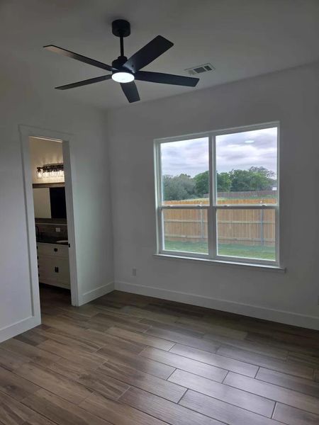 Unfurnished bedroom featuring dark wood finished floors, ceiling fan, and ensuite bath Unfurnished bedroom featuring dark wood finished floors, ceiling fan, and ensuite bath