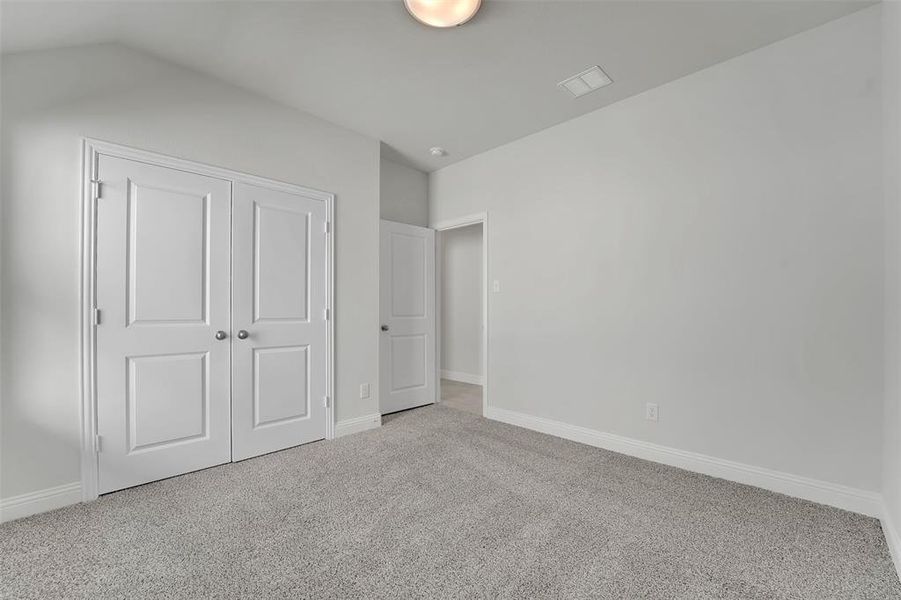 Unfurnished bedroom featuring a closet, carpet flooring, visible vents, and baseboards