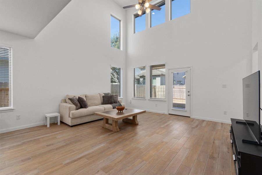 Living area with light wood-style floors, a ceiling fan, and a high ceiling