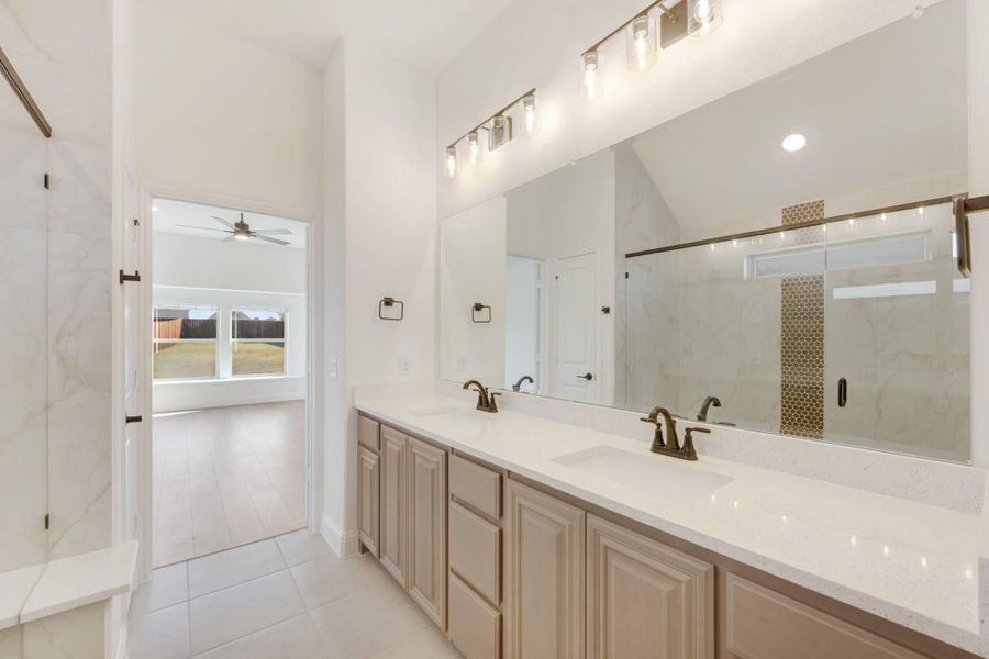 Master bathroom with double vanity, quartz countertops, large mirror, and glass shower enclosure with marble tile.