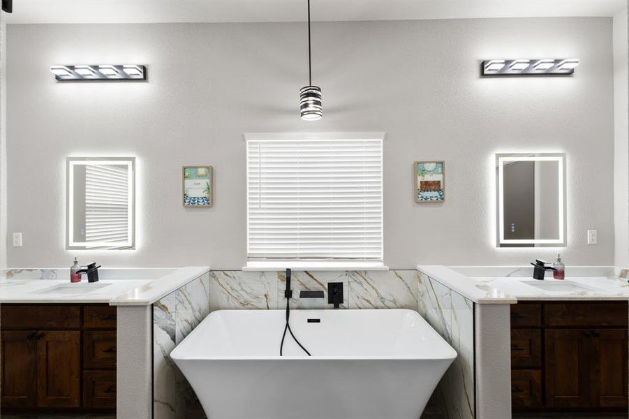 Bathroom with tile walls, a wainscoted wall, a freestanding tub, and two vanities