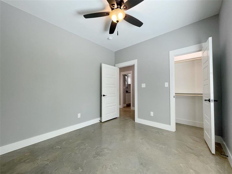 Unfurnished bedroom with a spacious closet, ceiling fan, and a closet