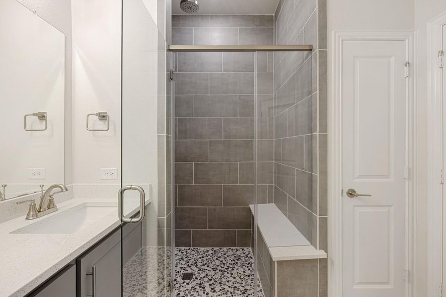 Bathroom with walk-in glass shower, gray tile walls, built-in bench, and white quartz vanity countertop Bathroom with walk-in glass shower, gray tile walls, built-in bench, and white quartz vanity countertop