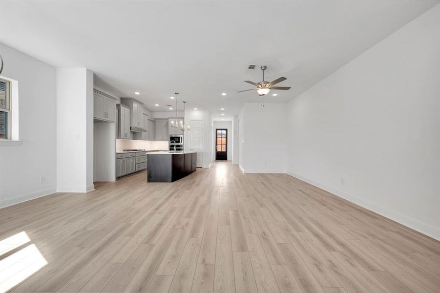 Unfurnished living room with a ceiling fan, light wood-style flooring, and hanging lights Unfurnished living room with a ceiling fan, light wood-style flooring, and hanging lights