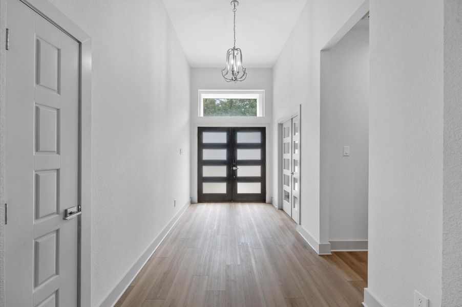 This entryway features a modern, spacious design with high ceilings and abundant natural light. It has sleek double doors, light wood flooring, and a contemporary chandelier, creating a welcoming atmosphere. This entryway features a modern, spacious design with high ceilings and abundant natural light. It has sleek double doors, light wood flooring, and a contemporary chandelier, creating a welcoming atmosphere.