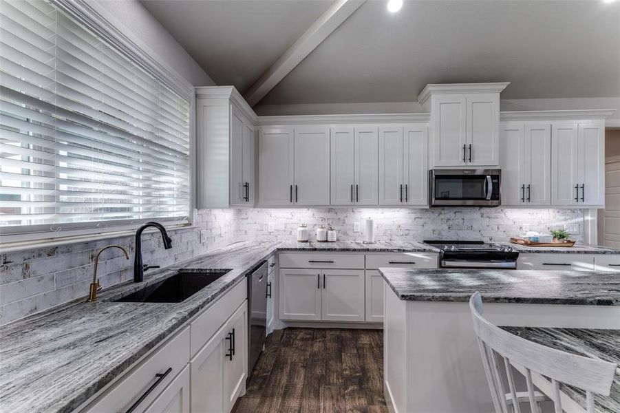 Kitchen with appliances with stainless steel finishes, white cabinets, and tasteful backsplash