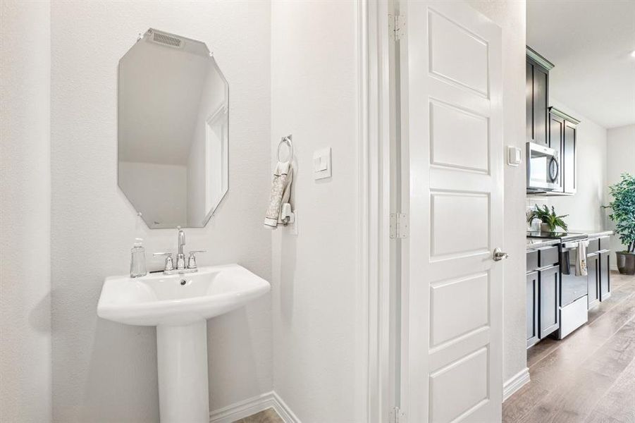 Half bathroom featuring baseboards and light wood-style flooring Half bathroom featuring baseboards and light wood-style flooring