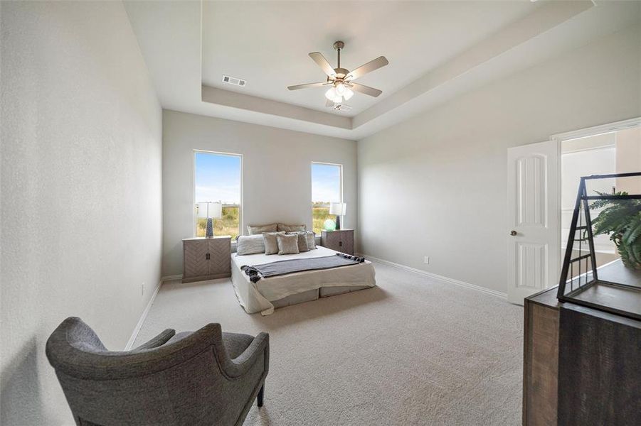 Bedroom featuring a tray ceiling, light carpet, and a ceiling fan Bedroom featuring a tray ceiling, light carpet, and a ceiling fan