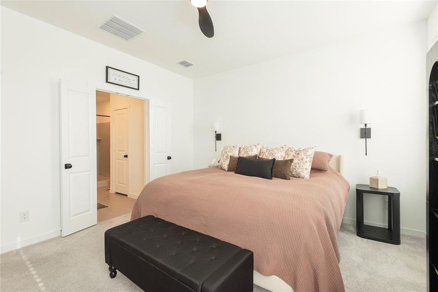 Spacious bedroom featuring light-colored carpeting, white walls, and a ceiling fan Spacious bedroom featuring light-colored carpeting, white walls, and a ceiling fan