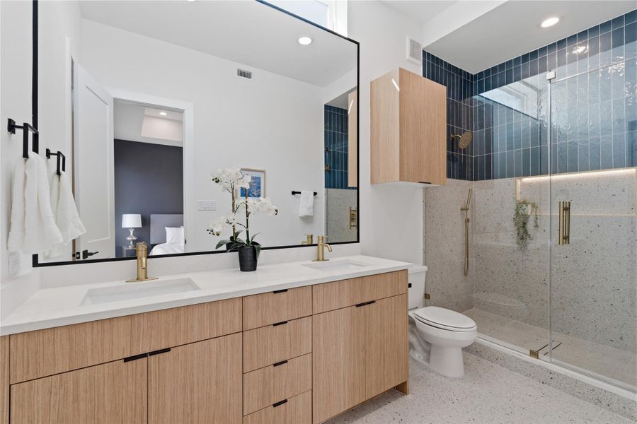 Duplex primary bath with dual vanities, modern finishes, and a large walk-in glass shower.
