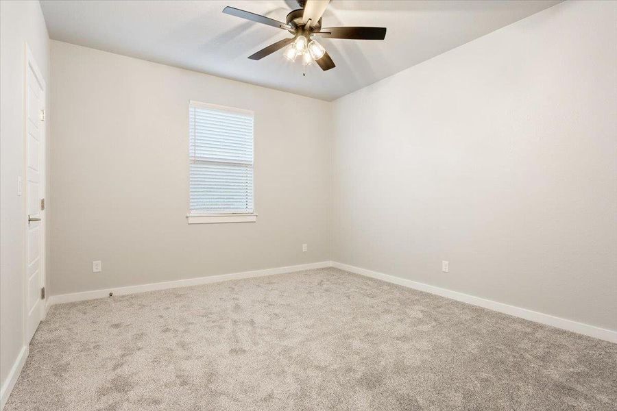 Carpeted empty room with baseboards and a ceiling fan Carpeted empty room with baseboards and a ceiling fan