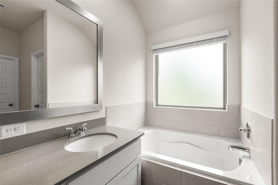 Positioned beneath a large privacy window, the soaking tub creates a bright and inviting space to unwind while allowing natural light to fill the room throughout the day.