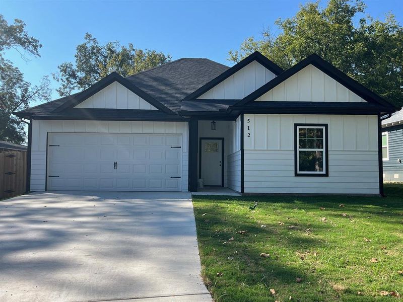 View of front of home featuring a front lawn, roof with shingles, driveway, a garage, and board and batten siding