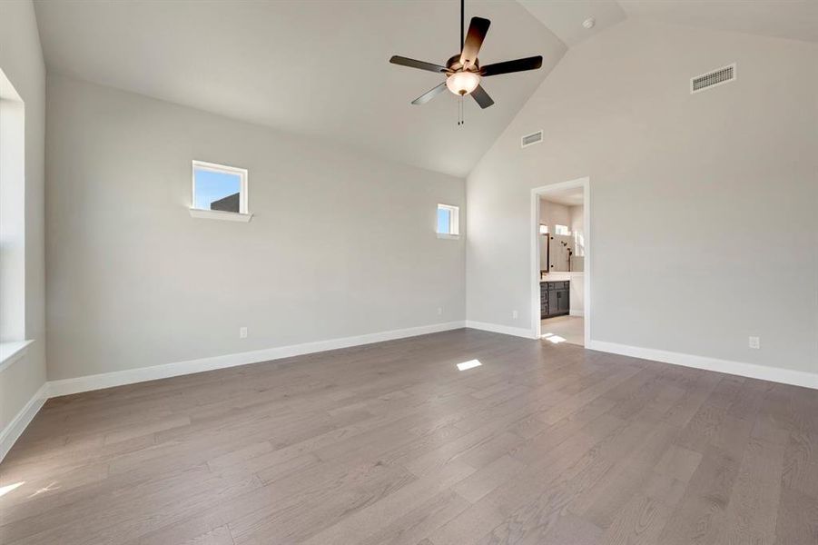 Spare room with ceiling fan, light wood finished floors, plenty of natural light, and vaulted ceiling Spare room with ceiling fan, light wood finished floors, plenty of natural light, and vaulted ceiling