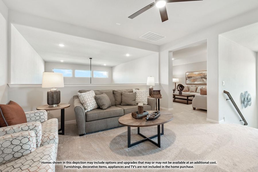 Carpeted living room with gray sofa, round wood coffee table, and ceiling fan, open to adjacent sitting area