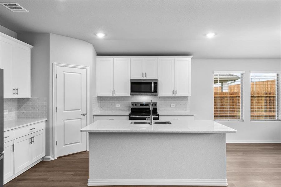 Kitchen featuring appliances with stainless steel finishes, dark wood-type flooring, decorative backsplash, white cabinets, and recessed lighting Kitchen featuring appliances with stainless steel finishes, dark wood-type flooring, decorative backsplash, white cabinets, and recessed lighting