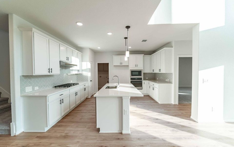 Kitchen featuring appliances with stainless steel finishes, white cabinetry, light wood-style floors, tasteful backsplash, and recessed lighting