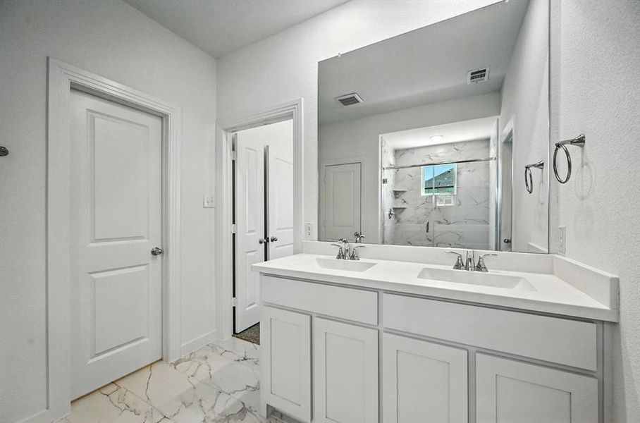 Full bathroom with light marble finish floors, a marble finish shower, and double vanity