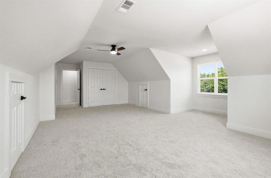 Spacious room featuring light-toned carpeting, white walls, and a ceiling fan with integrated lighting Spacious room featuring light-toned carpeting, white walls, and a ceiling fan with integrated lighting