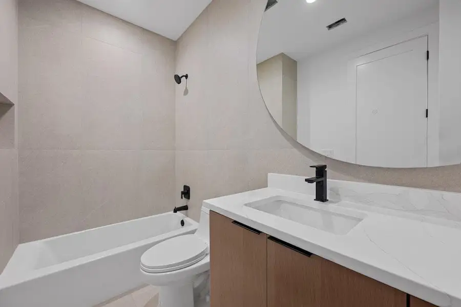 Bathroom with shower / tub combination, vanity, tile walls, and light tile patterned flooring