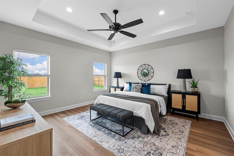 Bedroom featuring a raised ceiling, light wood finished floors, a ceiling fan, and recessed lighting Bedroom featuring a raised ceiling, light wood finished floors, a ceiling fan, and recessed lighting