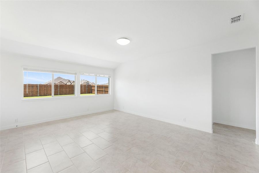 Empty room with light tile floors, white walls, and a window overlooking a fenced backyard