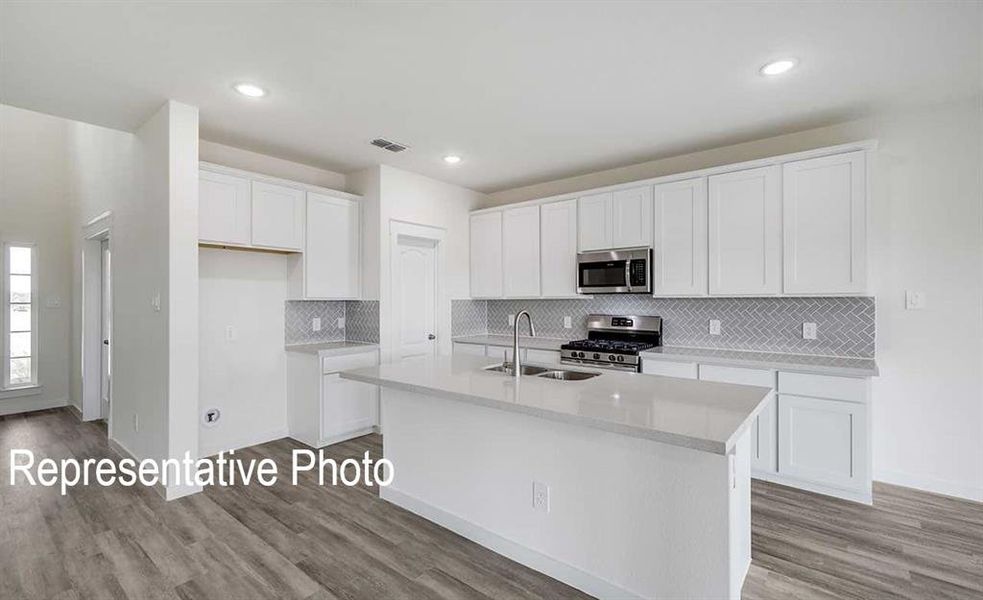 Kitchen featuring a center island with sink, appliances with stainless steel finishes, and white cabinetry