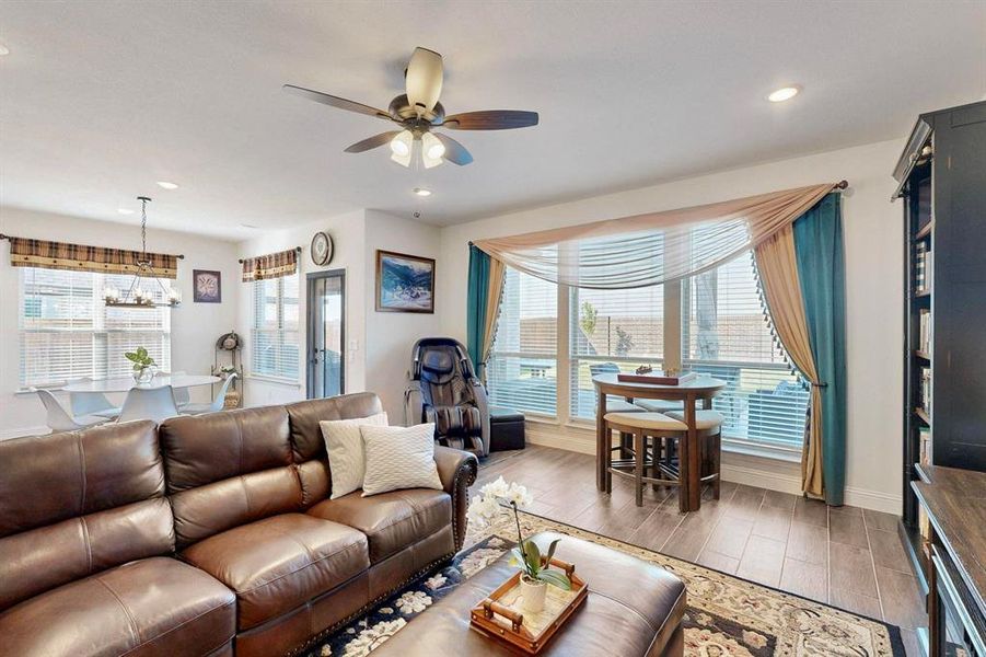 Living room featuring light wood-style floors, recessed lighting, ceiling fan, and a chandelier