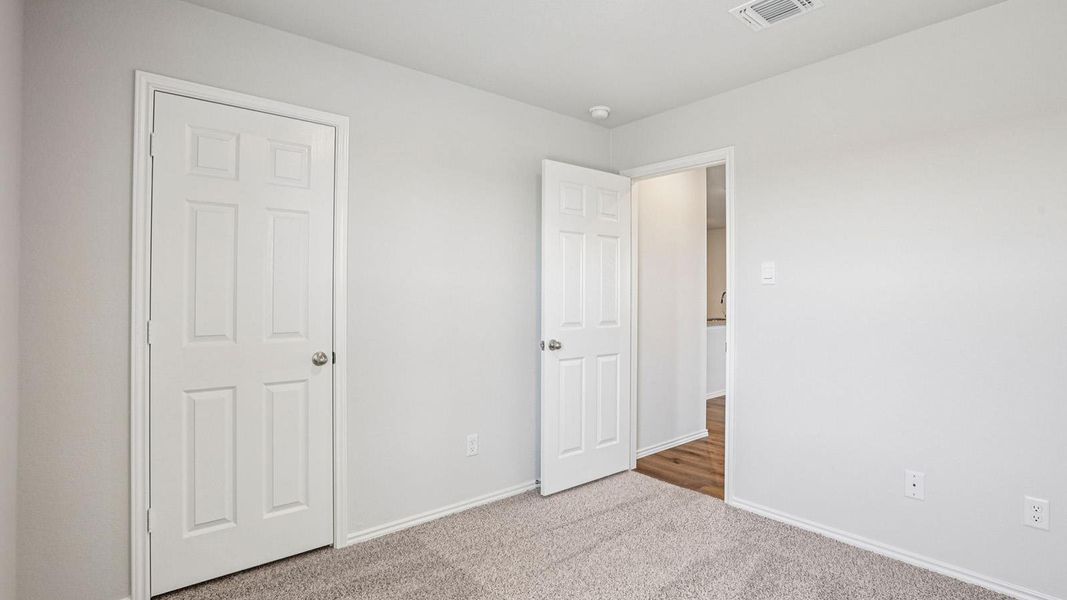 Carpeted room featuring light gray walls, white trim, and a six-panel interior door Carpeted room featuring light gray walls, white trim, and a six-panel interior door
