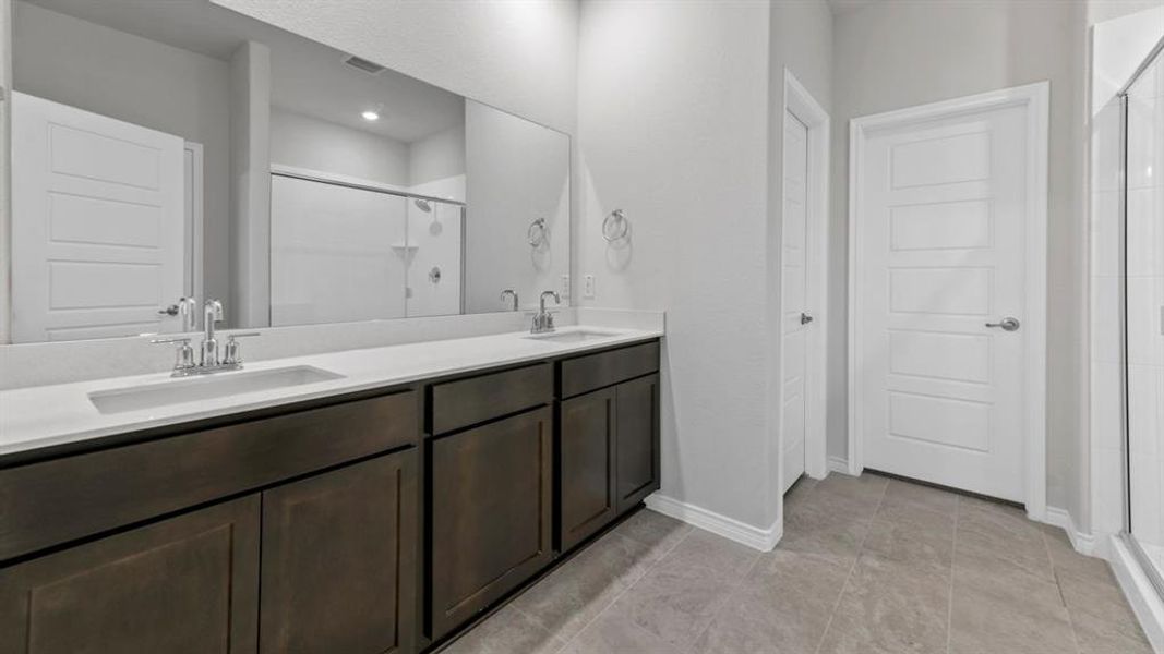 Bathroom featuring a dual vanity with dark wood-finish cabinetry and light-toned countertops