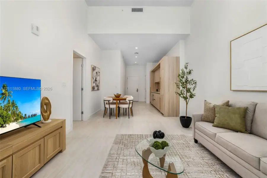 Open-concept interior featuring high ceilings, light-toned wood-finish flooring, and recessed lighting