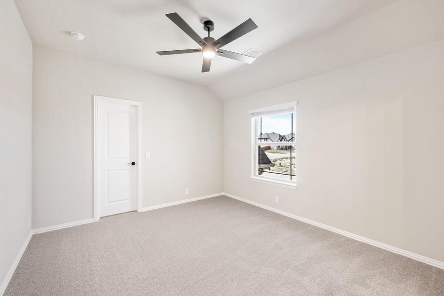 Empty bedroom with carpet flooring, ceiling fan, vaulted ceiling, and single window with natural light