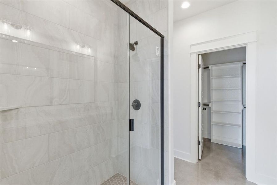 Bathroom with a stall shower, finished concrete floors, and a spacious closet