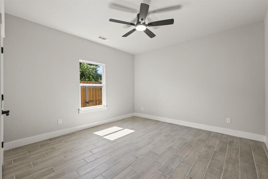 Empty room with wood finished floors, a ceiling fan, and baseboards