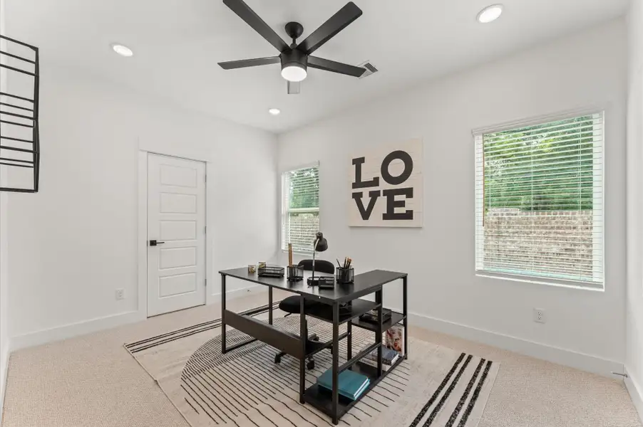 Versatile secondary bedroom on the first floor, thoughtfully staged as a home office yet adaptable to suit any lifestyle need. The space boasts warm natural light and easy access to a shared Jack and Jill bathroom, adding both function and privacy.