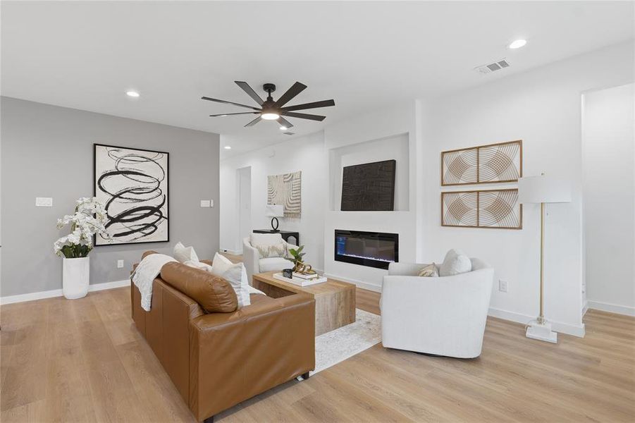 Living room with a ceiling fan, a glass covered fireplace, light wood-style flooring, and recessed lighting Living room with a ceiling fan, a glass covered fireplace, light wood-style flooring, and recessed lighting