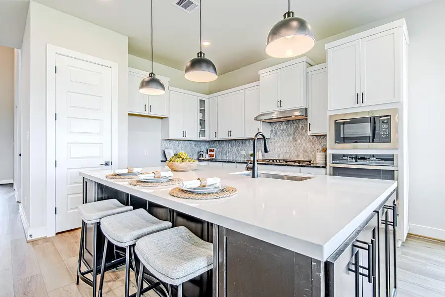 A modern culinary dream—this kitchen features a spacious island with seating, matte black hardware, and a sophisticated backsplash that adds texture and elegance.