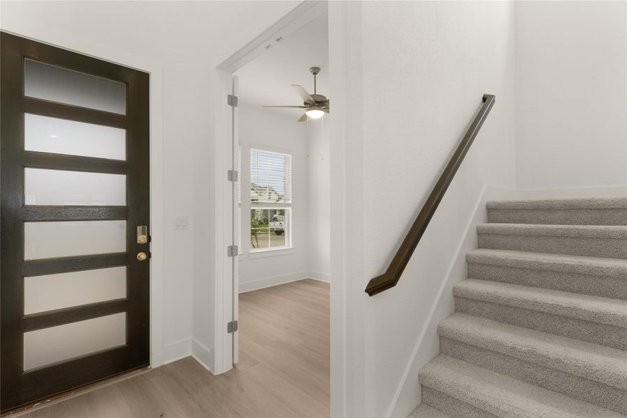 Foyer entrance with light wood-type flooring, stairs, and a ceiling fan