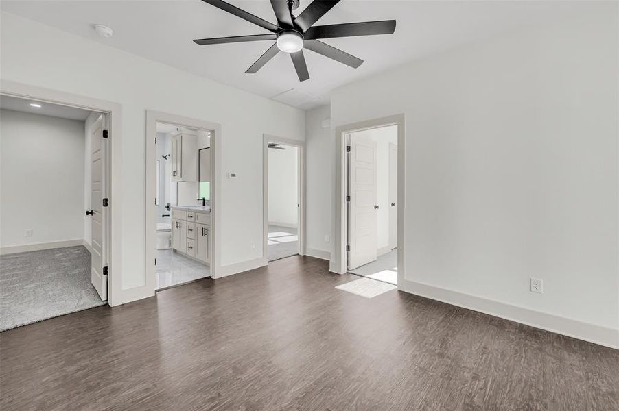 Unfurnished bedroom with dark wood finished floors, ceiling fan, and ensuite bathroom