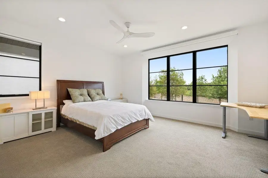 Spacious room with large multi-pane windows, light-toned carpeting, recessed lighting, and a ceiling fan